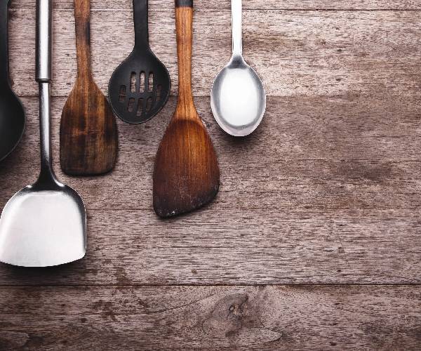 A wooden table with spoons and spatulas on it