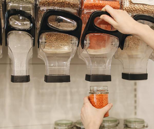 A person holding a jar of food in front of a wall.